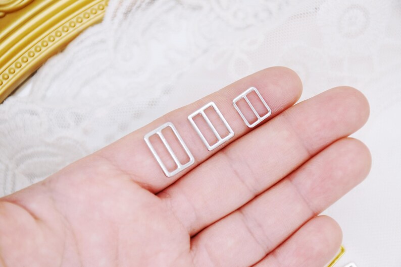 May include: Three silver metal slider buckles of different sizes. The buckles are rectangular with a small opening in the center.