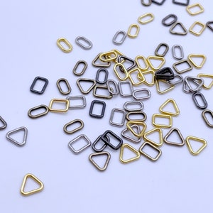 May include: Assortment of small metal rings and triangles in gold, silver, and black.
