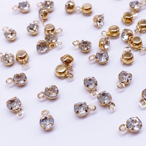 May include: A collection of gold-toned metal charms with clear crystal rhinestones. Each charm has a loop at the top and a small loop at the bottom.