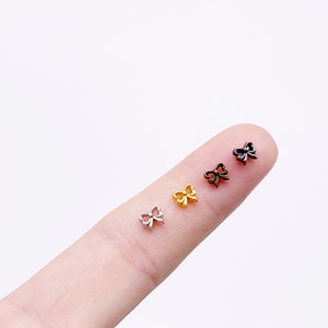 May include: Four small bow-shaped charms in silver, gold, bronze, and black.
