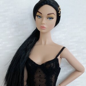 May include: A fashion doll with long black hair styled in a ponytail, wearing a black lace bodysuit and a gold hair clip.
