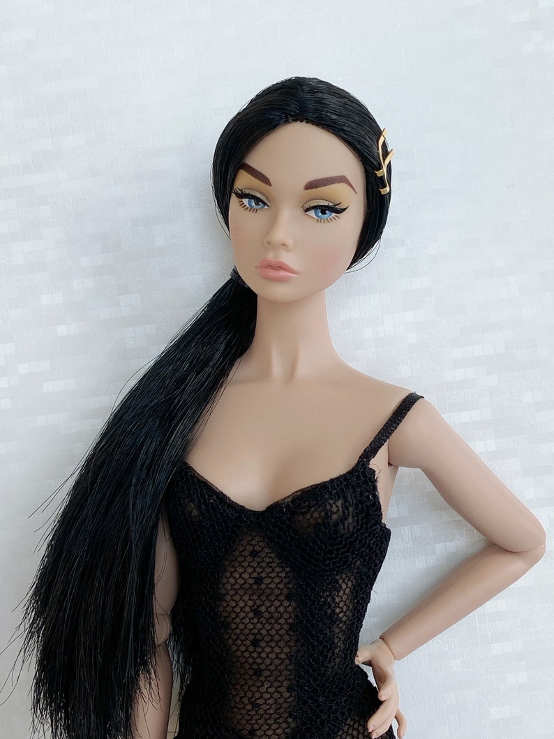 May include: A fashion doll with long black hair styled in a ponytail, wearing a black lace bodysuit and a gold hair clip.