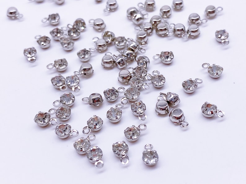 May include: A scattering of silver-toned metal charms with clear crystal rhinestones. Each charm has a loop for attaching to jewelry or other crafts.