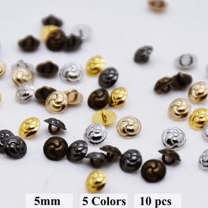 May include: Assortment of 10 small, 5mm, decorative buttons in five colors: gold, silver, black, bronze, and copper. The buttons have a swirl design.