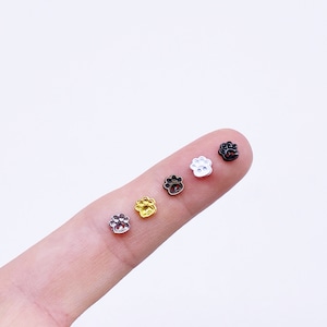 May include: Four small metal paw print charms in gold, silver, black, and white.