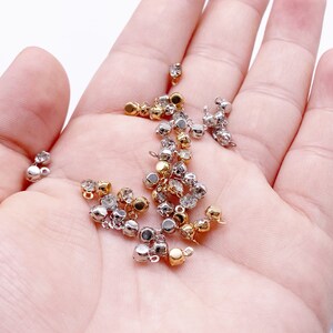 May include: A collection of gold and silver metal bead caps with clear rhinestones. The bead caps have a loop on the top for attaching to jewelry.