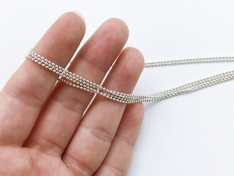 May include: A silver chain necklace with multiple strands of small, round beads.