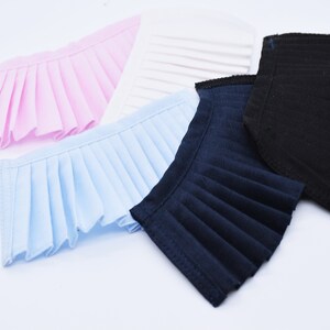 May include: Four fabric collars in different colors: pink, light blue, navy blue, and black. Each collar is pleated and has a scalloped edge.