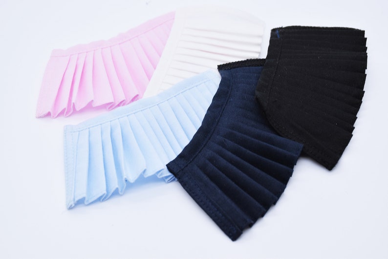 May include: Four fabric collars in different colors: pink, light blue, navy blue, and black. Each collar is pleated and has a scalloped edge.