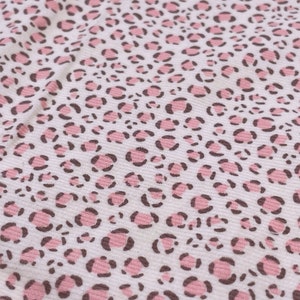Op de afbeelding: Witte stof met een roze en bruin luipaardprintpatroon.