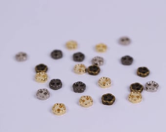 May include: A collection of small, flower-shaped buttons in various metallic finishes, including gold, silver, and bronze. Each button has two holes for sewing and a slightly raised center. The buttons are scattered on a white surface.