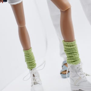 Puede incluir: Un par de botas blancas con calcetines verdes. Las botas tienen cordones y una suela blanca. Los calcetines son de canalé y llegan justo debajo de la rodilla.