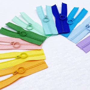 May include: Assortment of colorful zipper pulls in a rainbow pattern. The zipper pulls are made of plastic and have a variety of colors, including pink, yellow, green, blue, and purple.