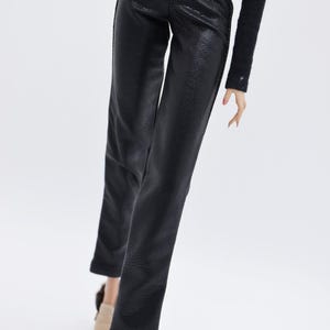 May include: Black leather pants with a textured surface. The pants have a high waist and a straight leg.