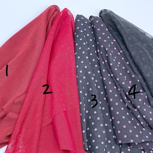 May include: Five different fabric swatches, numbered 1 through 5. The swatches are arranged horizontally. The first two swatches are red, the third and fourth swatches are black with white polka dots, and the fifth swatch is black lace.