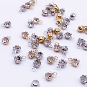May include: Assortment of clear crystal rhinestone connectors with gold and silver settings. The connectors have a loop on the top for attaching to jewelry or other crafts.