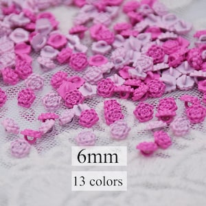 May include: Assortment of 6 mm pink and purple flower-shaped buttons. There are 13 different colours of buttons in the image. 6mm 13 colours