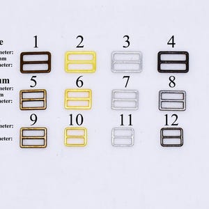May include: Twelve metal slider buckles in three sizes: large, medium, and small. The buckles are in three finishes: antique brass, gold, and silver. The buckles are numbered 1 through 12.