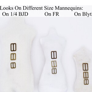 May include: Three white fabric mannequins of different sizes, each with three gold-colored metal slider buckles attached to the front. The mannequins are labeled "On 1/4 BJD", "On FR", and "On Blythe".