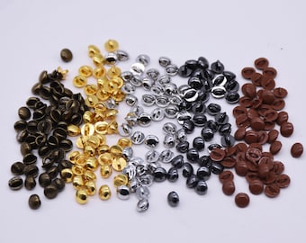 May include: Assortment of small, round, metal buttons in various colors, including bronze, gold, silver, black, and brown.