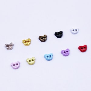 May include: Assortment of ten small bear-shaped buttons in various colors, including gold, silver, black, white, red, pink, yellow, and blue.