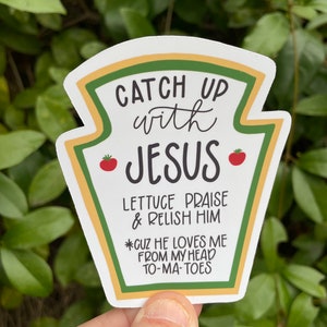 May include: A white sticker with a ketchup bottle design. The sticker says "Catch Up with Jesus" and has the text "Lettuce Praise & Relish Him *Cuz He Loves Me From My Head To-Ma-Toes".