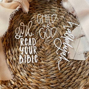 May include: Three clear acrylic bookmarks with white lettering. The bookmarks say "girl, read your bible", "child of god", and "blessed" in a handwritten font.