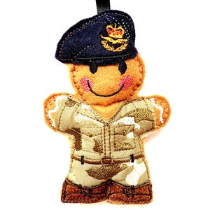 May include: A gingerbread person ornament wearing a blue military hat with a crown and a camouflage uniform.