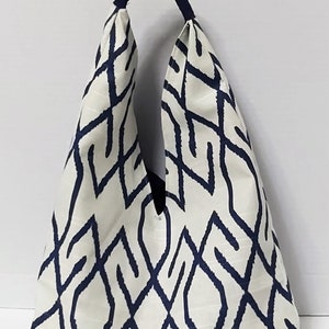May include: A white and navy blue tote bag with a geometric pattern. The bag has a single handle that is made of navy blue fabric.