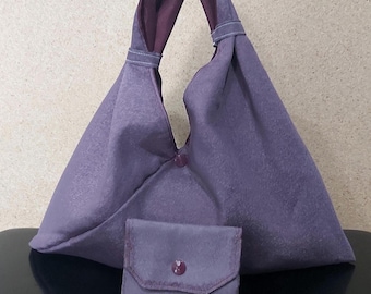 May include: A lavender-colored tote bag and matching wallet set. The tote bag has a unique triangular shape with a handle and a button closure. The wallet is small and square, with a button closure and a contrasting stitch.