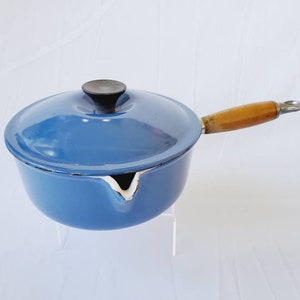 May include: A blue enamel cast iron saucepan with a wooden handle and a lid. The saucepan has a pouring spout.