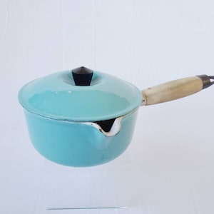 May include: A turquoise blue enamel cast iron saucepan with a wooden handle and a black knob on the lid.