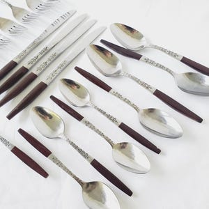 May include: Set of silverware with brown wooden handles. The silverware includes spoons, forks, and knives.