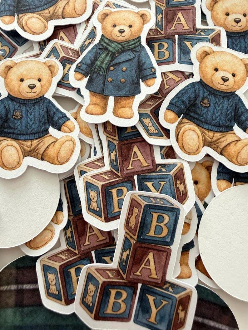 May include: A collection of stickers featuring watercolor illustrations of teddy bears in various outfits, including a blue sweater and a navy coat with a green scarf. Also included are alphabet blocks with the letters A, B, and Y.
