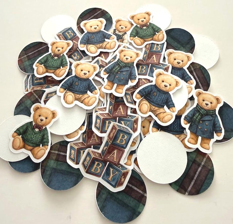 May include: A collection of paper cutouts featuring teddy bears in various outfits, including sweaters and coats. The bears are interspersed with ABC blocks and plaid and white circles. The color palette includes shades of brown, blue, green, and white.