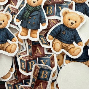 May include: A collection of stickers featuring watercolor illustrations of teddy bears in various outfits, including a blue coat and a sweater. The stickers are interspersed with alphabet blocks, creating a playful and nostalgic theme.