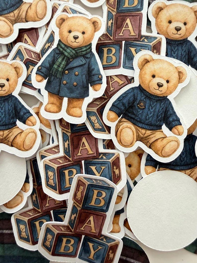 May include: A collection of stickers featuring watercolor illustrations of teddy bears in various outfits, including a blue coat and a sweater. The stickers are interspersed with alphabet blocks, creating a playful and nostalgic theme.