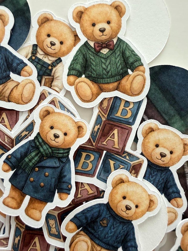 May include: A collection of die-cut stickers featuring teddy bears in various outfits. The bears are depicted in a range of attire, including sweaters, coats, and overalls. Some stickers include alphabet blocks. The color palette includes shades of brown, blue, and green.