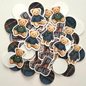 May include: A collection of teddy bear stickers and cutouts, some wearing sweaters and coats, with wooden alphabet blocks and plaid and white circles. The bears are in various poses, with some wearing bow ties and scarves.