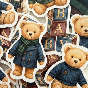 May include: A collection of teddy bear stickers in various outfits, including a blue coat with a green scarf, a green sweater, and overalls. The bears are surrounded by alphabet blocks.