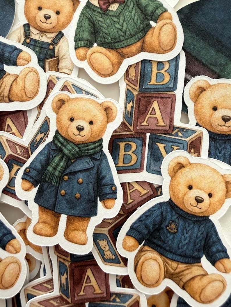 May include: A collection of teddy bear stickers in various outfits, including a blue coat with a green scarf, a green sweater, and overalls. The bears are surrounded by alphabet blocks.