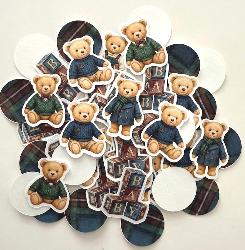 May include: A collection of teddy bear stickers in various outfits, including sweaters and coats, with wooden blocks spelling "BABY". The bears are surrounded by white circles and plaid patterned circles in shades of blue, green, and brown.