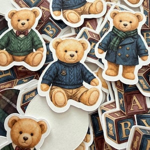 May include: A collection of die-cut stickers featuring teddy bears in various outfits. The bears are wearing sweaters, coats, and bow ties. Wooden alphabet blocks with the letters A and B are scattered around the stickers.