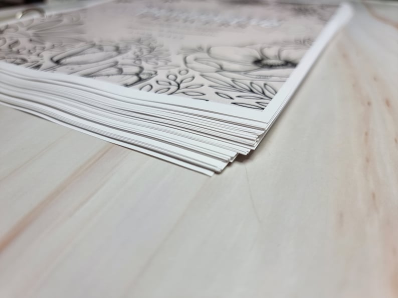 May include: A stack of white paper with a black and grey floral design printed on the top sheet.