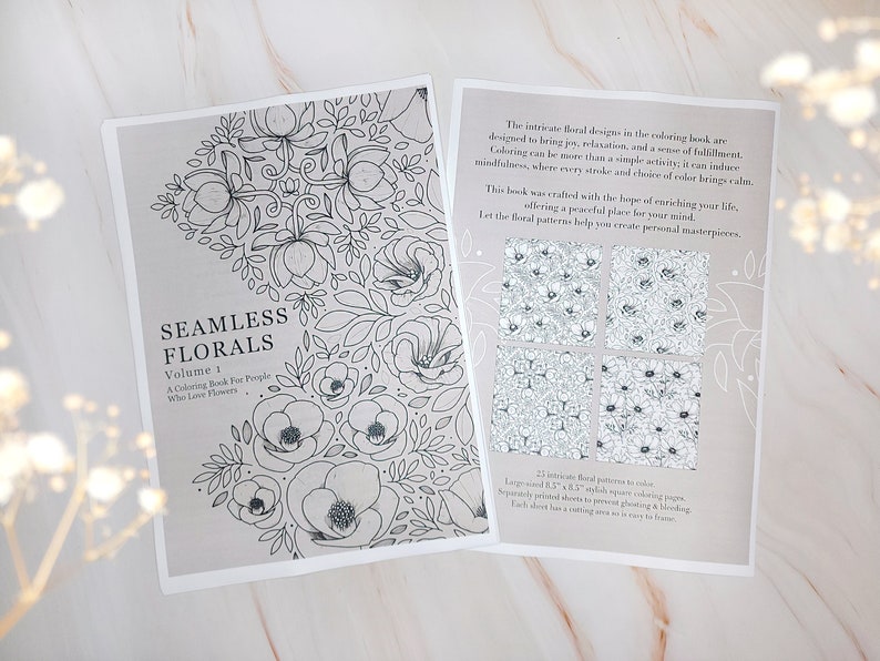 Op de afbeelding: Een kleurboek met de titel "Seamless Florals, Volume 1: A Coloring Book for People Who Love Flowers". De omslag toont een zwart-witte illustratie van een bloemenpatroon. De achterkant van het boek toont vier voorbeelden van de bloemenpatronen die in het boek zijn opgenomen.