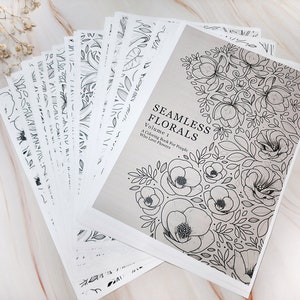 Op de afbeelding: Een kleurboek met de titel "Seamless Florals, Volume 1: A Coloring Book For People Who Love Flowers". De omslag toont een zwart-witte illustratie van een bloemenpatroon.