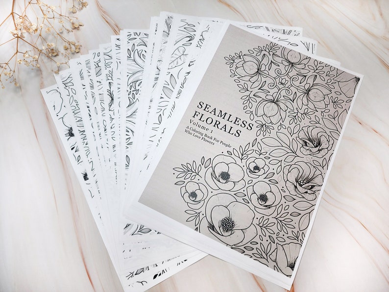 Op de afbeelding: Een kleurboek met de titel "Seamless Florals, Volume 1: A Coloring Book For People Who Love Flowers". De omslag toont een zwart-witte illustratie van een bloemenpatroon.
