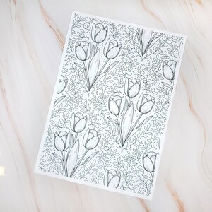 Op de afbeelding: Een zwart-witte lijntekening van een herhalend patroon van tulpen en bladeren. De tulpen zijn getekend in een eenvoudige, elegante stijl.