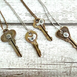 May include: Four gold key necklaces with silver charms. Each charm has a different letter on it: M, S, O, and K.