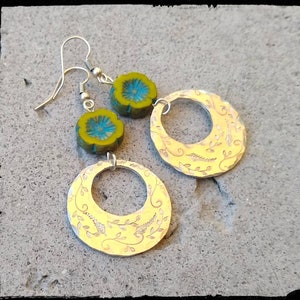 May include: A pair of silver earrings with a floral design and a green and blue flower bead on each earring.